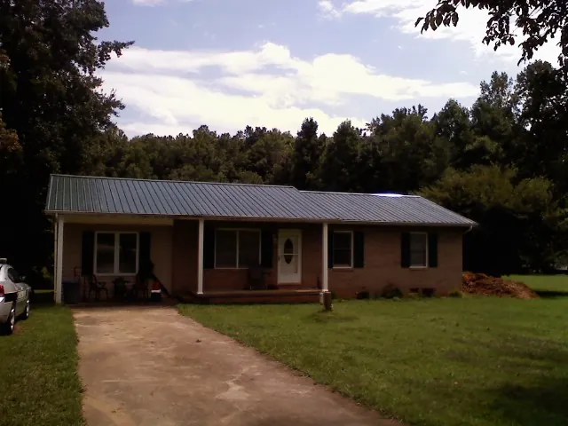 Dark green metal roof on a brick ranch with a covered porch in Lake Park