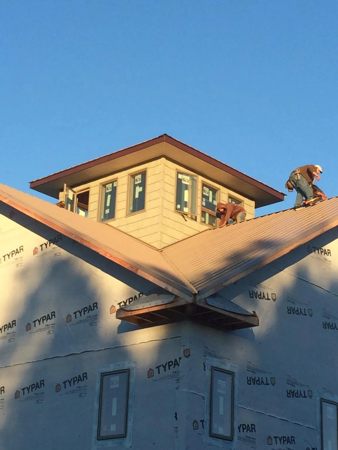 Roofers working around a rooftop cupola on a new metal roof at sunset — Roof Waterproofing in Lake Park by Roofing Brothers